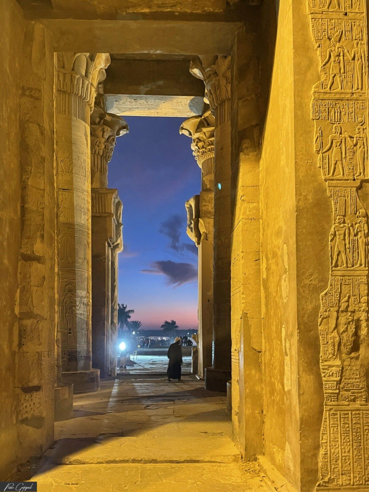 Passage encadré de colonnes gravées avec silhouette au loin