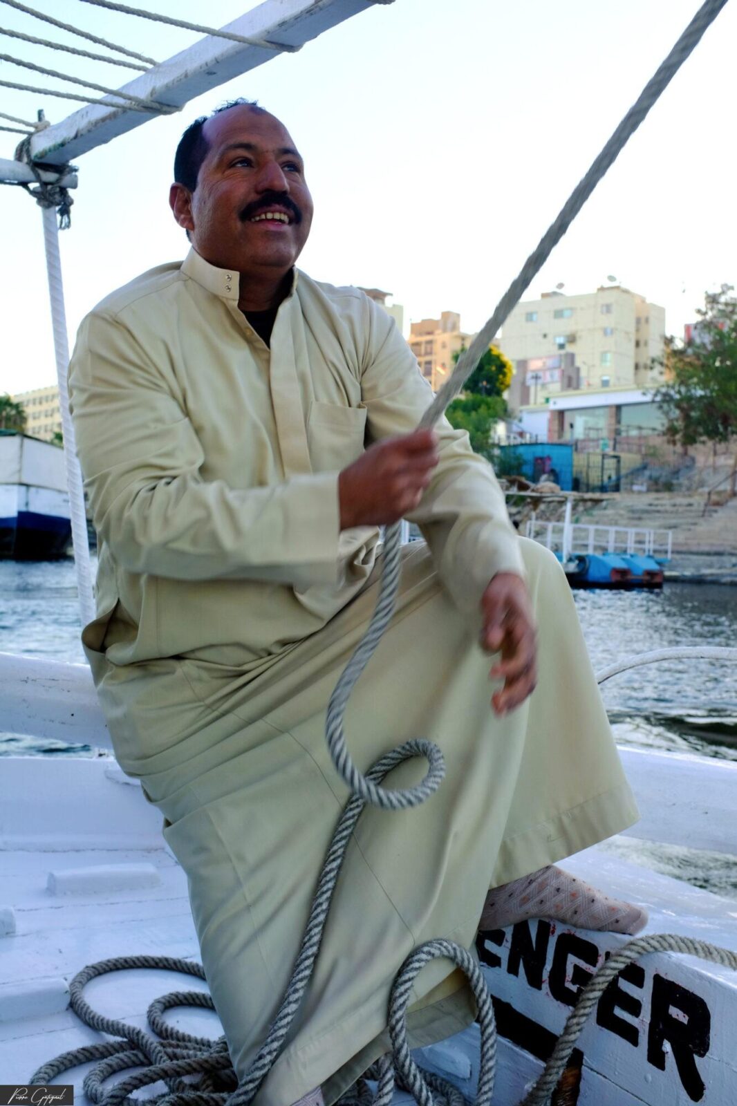 Homme assis sur un bateau, tenant une corde