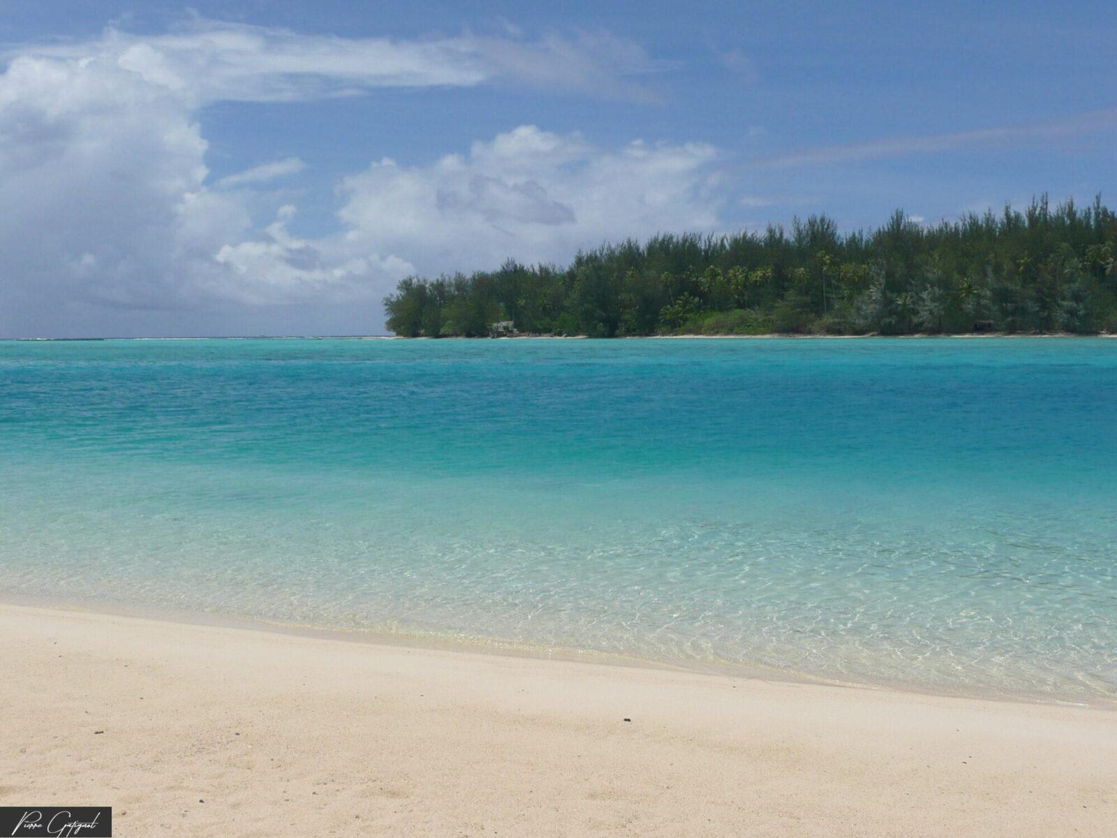 Plage de sable clair face à un lagon turquoise