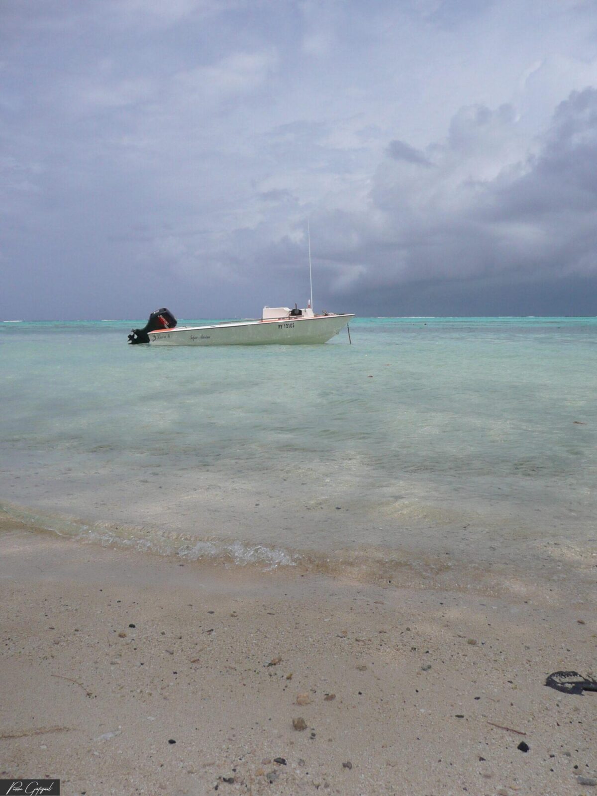 Petit bateau blanc sur une mer turquoise sous ciel nuageux