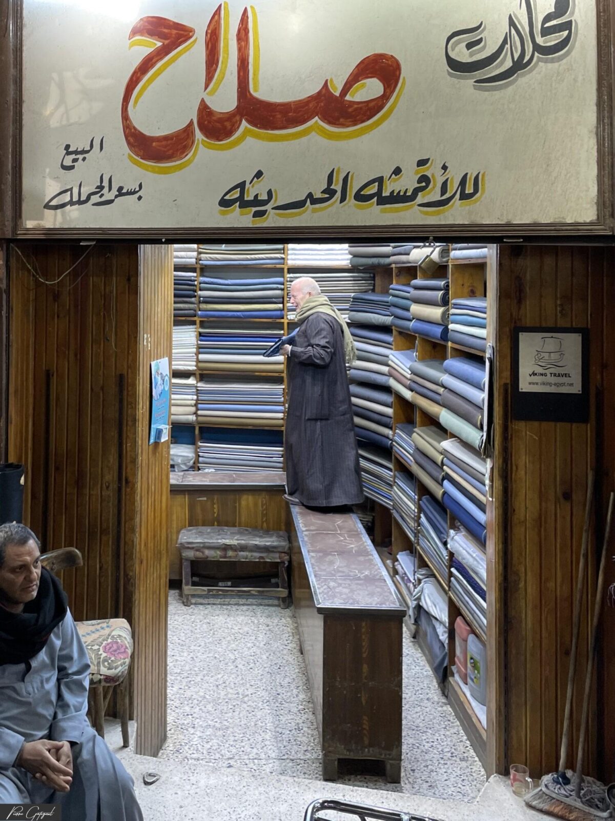 Homme dans une boutique étroite bordée de rouleaux de tissu