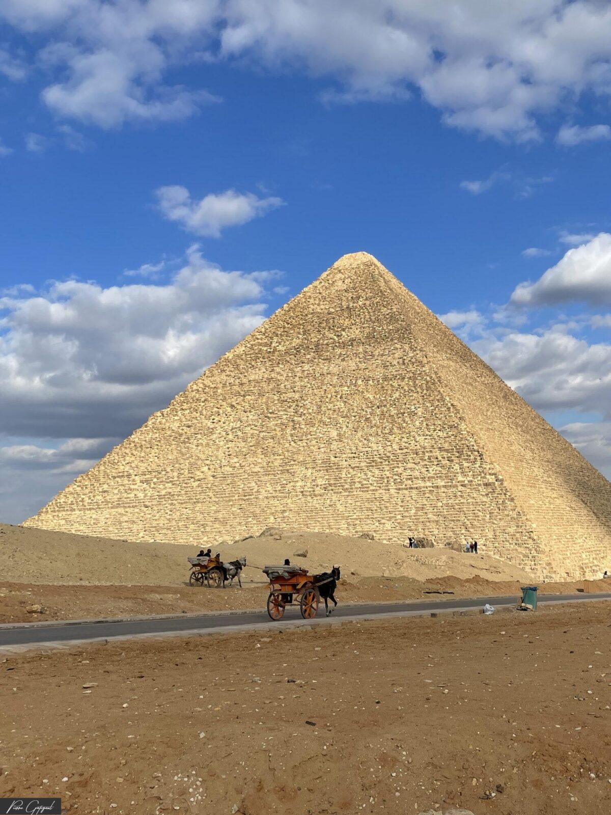 Pyramide sous un ciel nuageux, avec deux calèches au premier plan