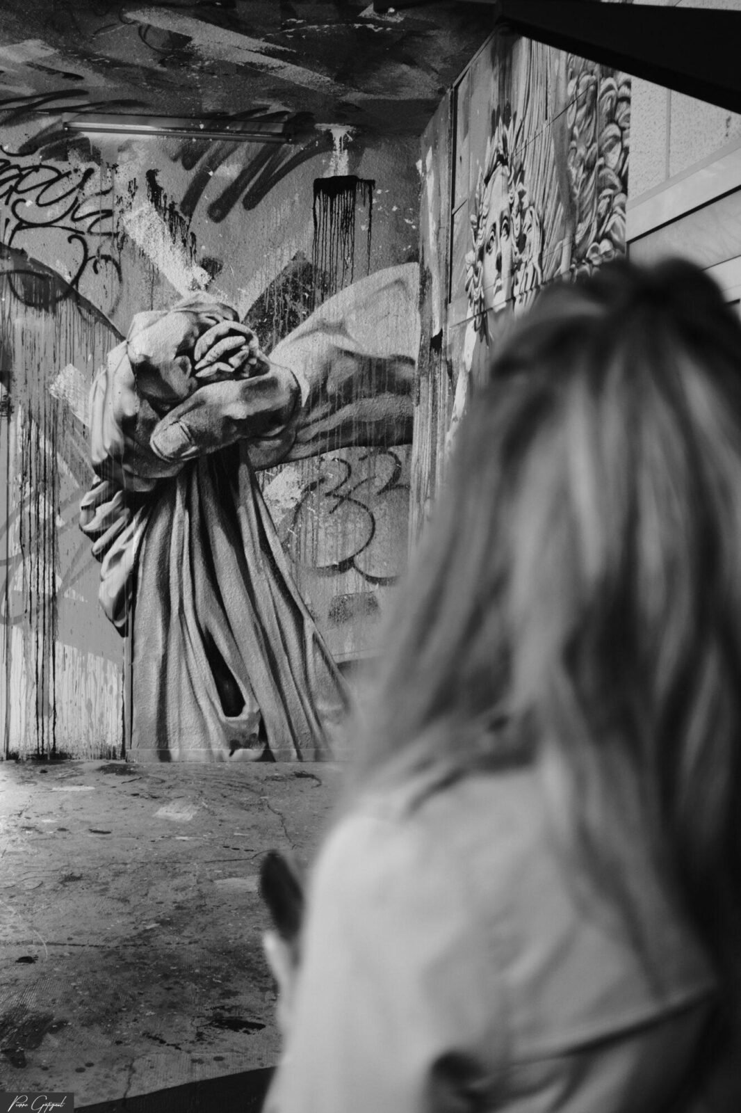Femme de dos observant une fresque avec une sculpture