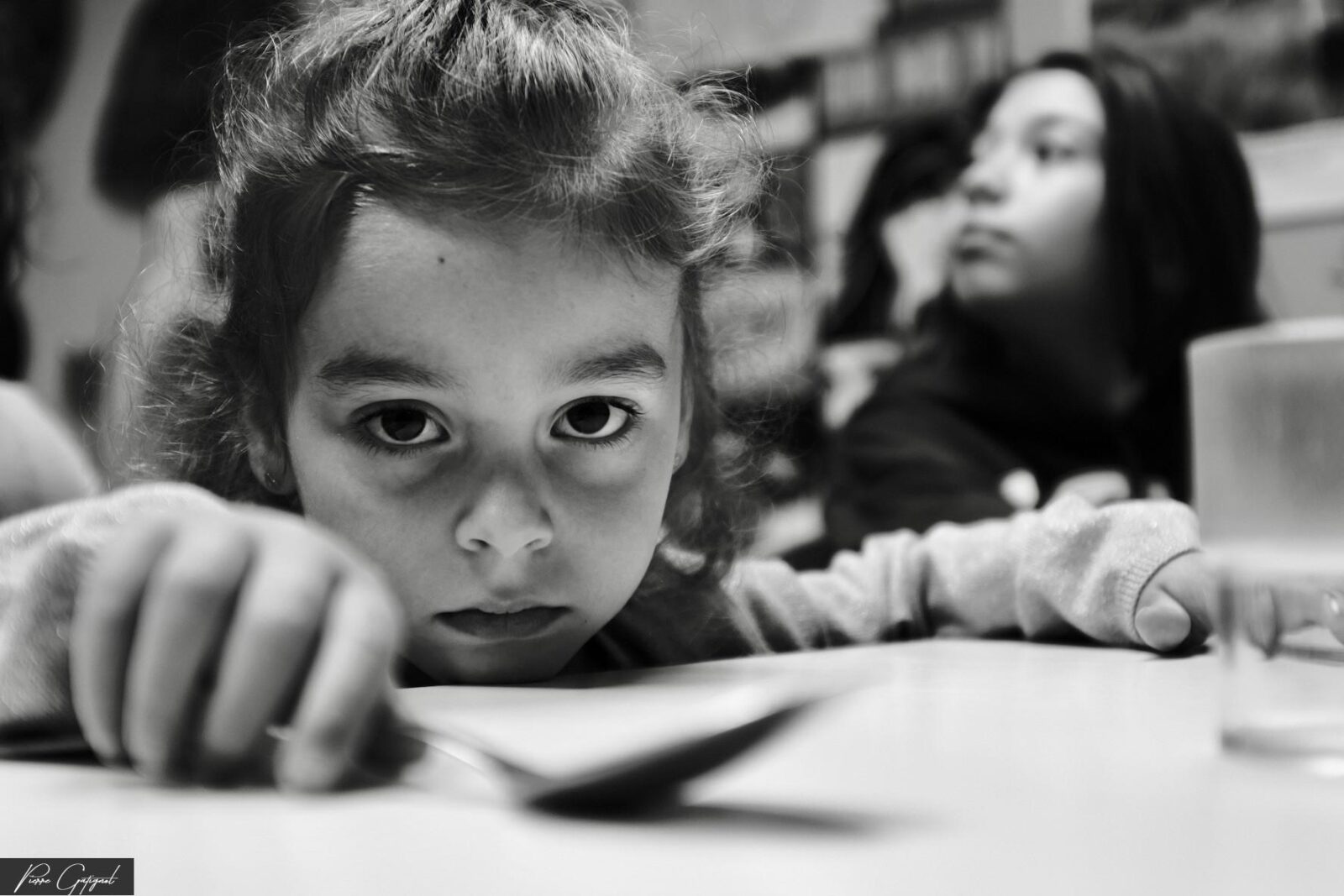 Enfant regardant l’objectif, les mains posées sur une table