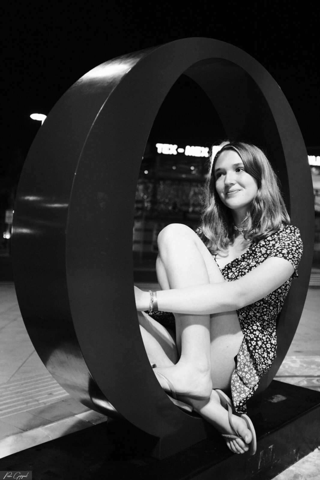 Femme assise dans une grande structure circulaire, de nuit