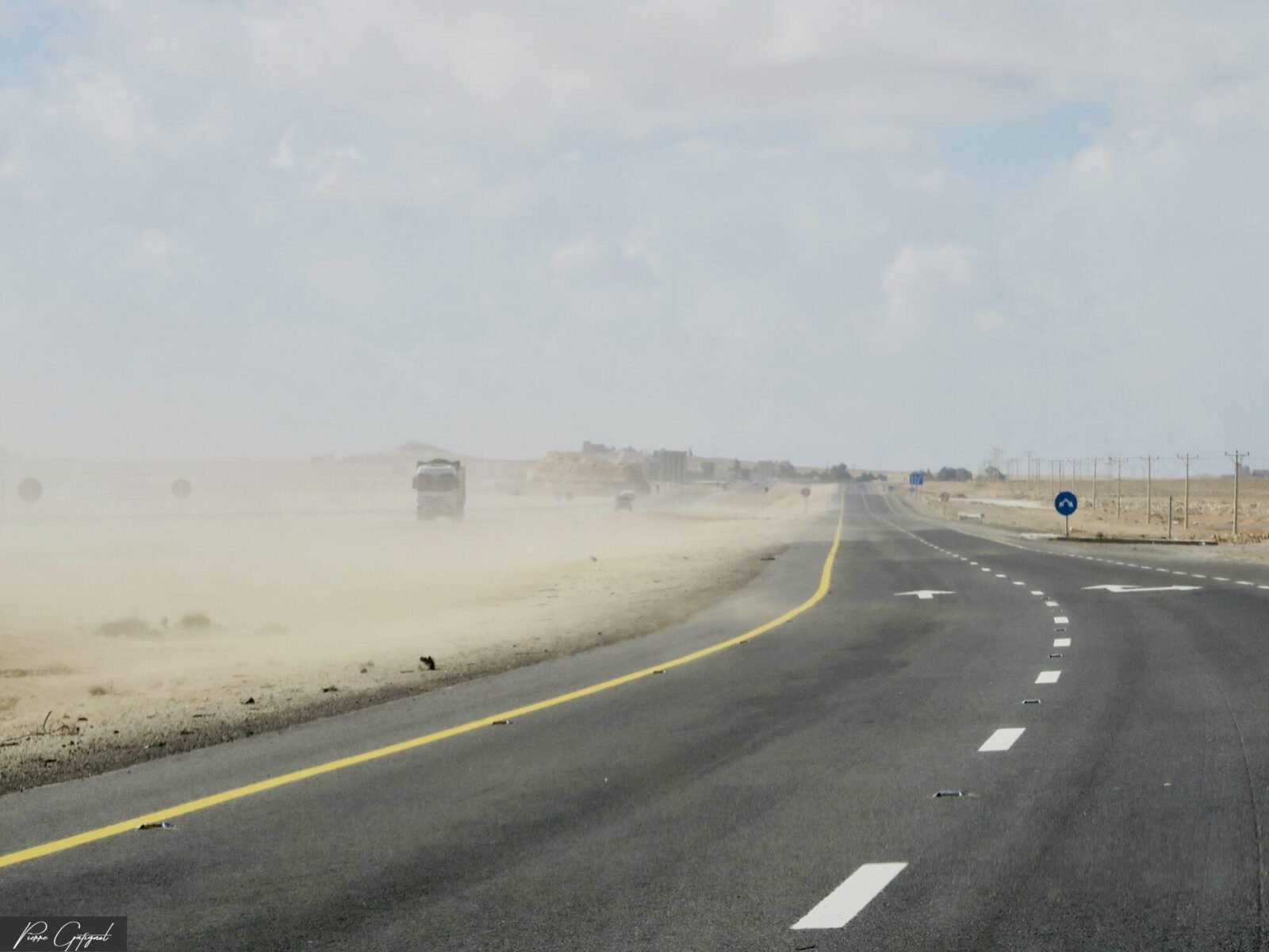 Route asphaltée traversant un paysage désertique poussiéreux