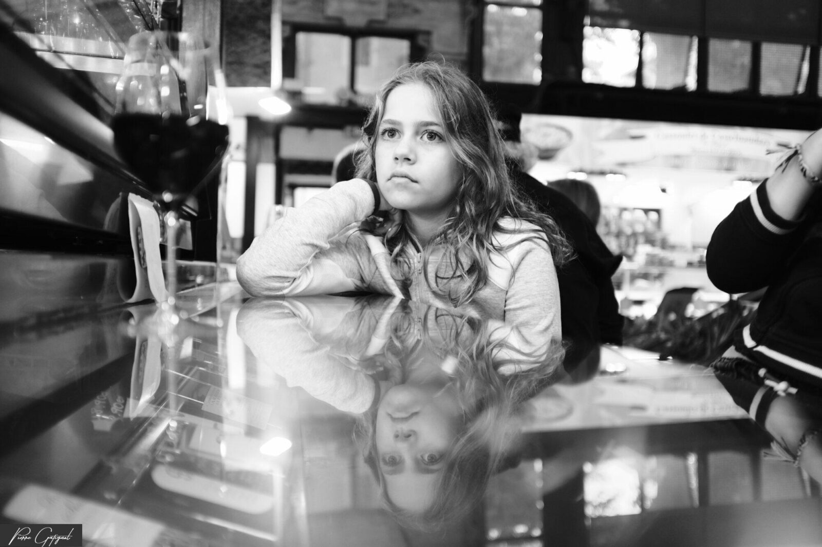 Jeune femme assise au comptoir, le visage reflété sur la surface
