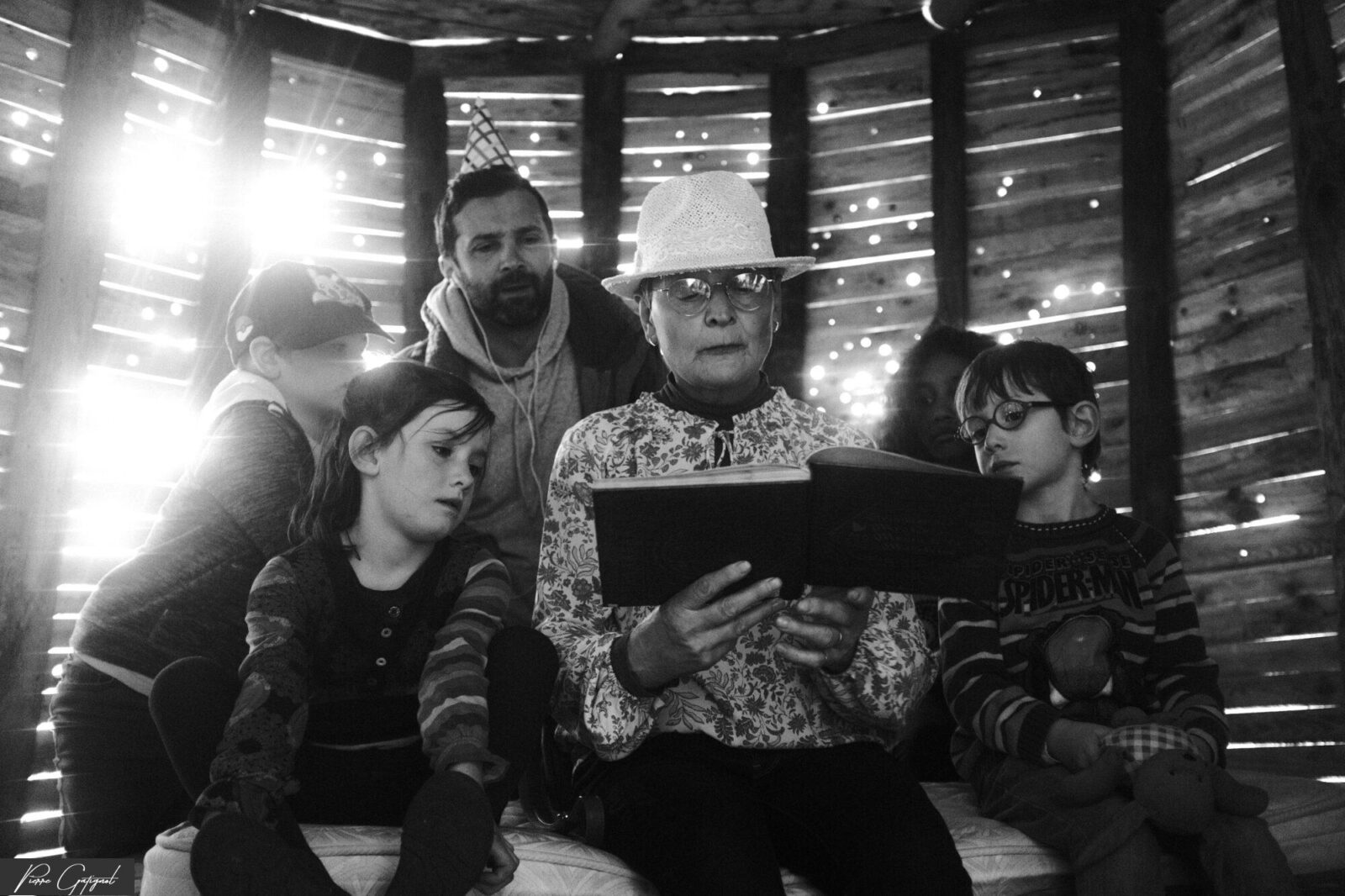 Cinq personnes réunies autour d’un livre dans une cabane en bois