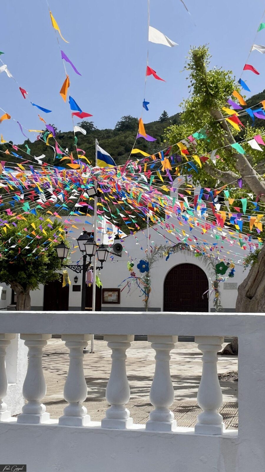 Fanions multicolores devant une façade blanche et un balcon
