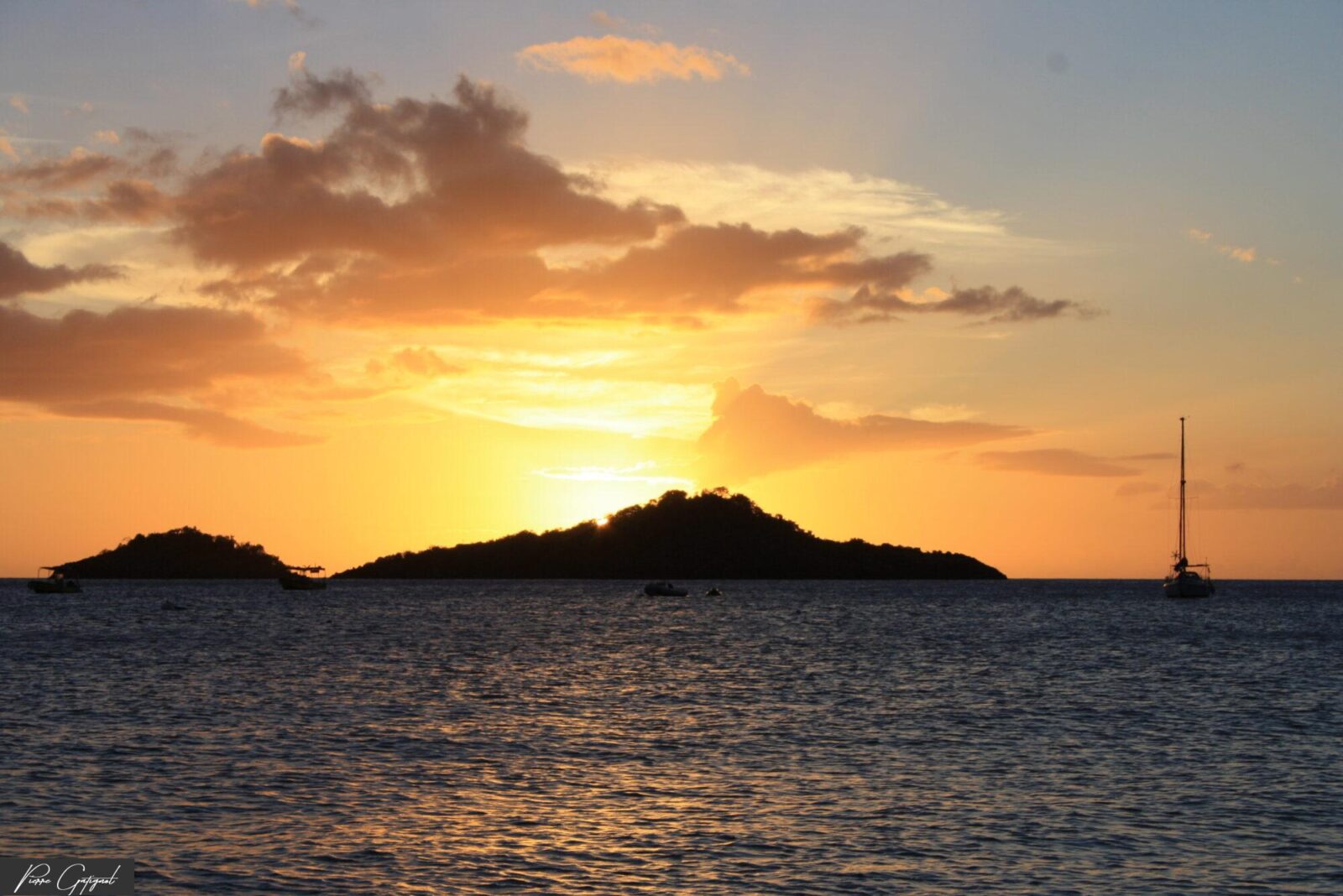 Coucher de soleil sur la mer, îlots sombres et voilier