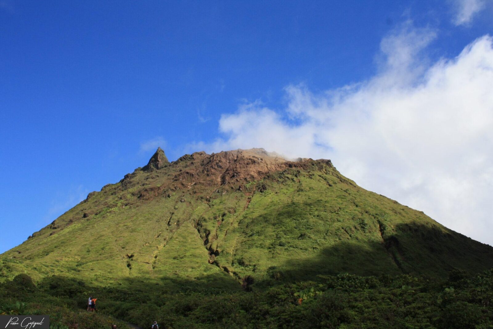 Sommet escarpé couvert d’herbe sous un ciel bleu nuageux