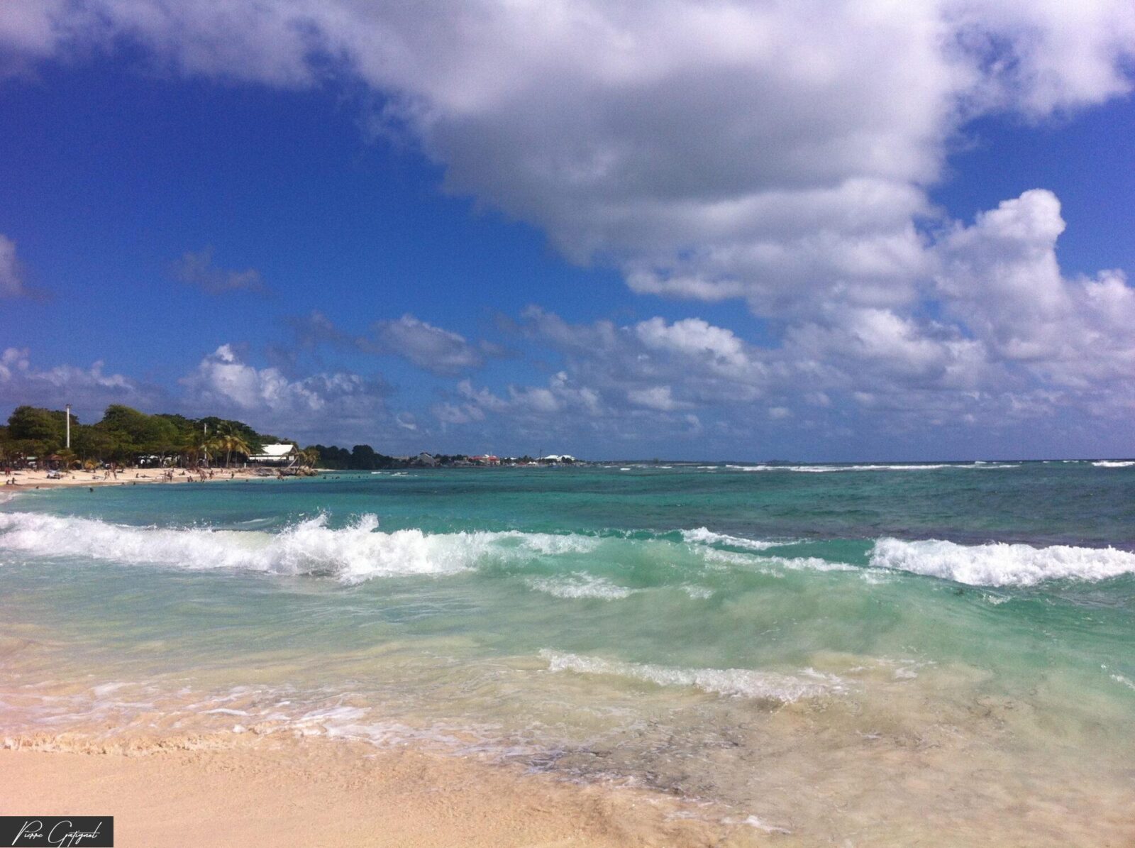 Vagues sur une plage et mer turquoise sous les nuages