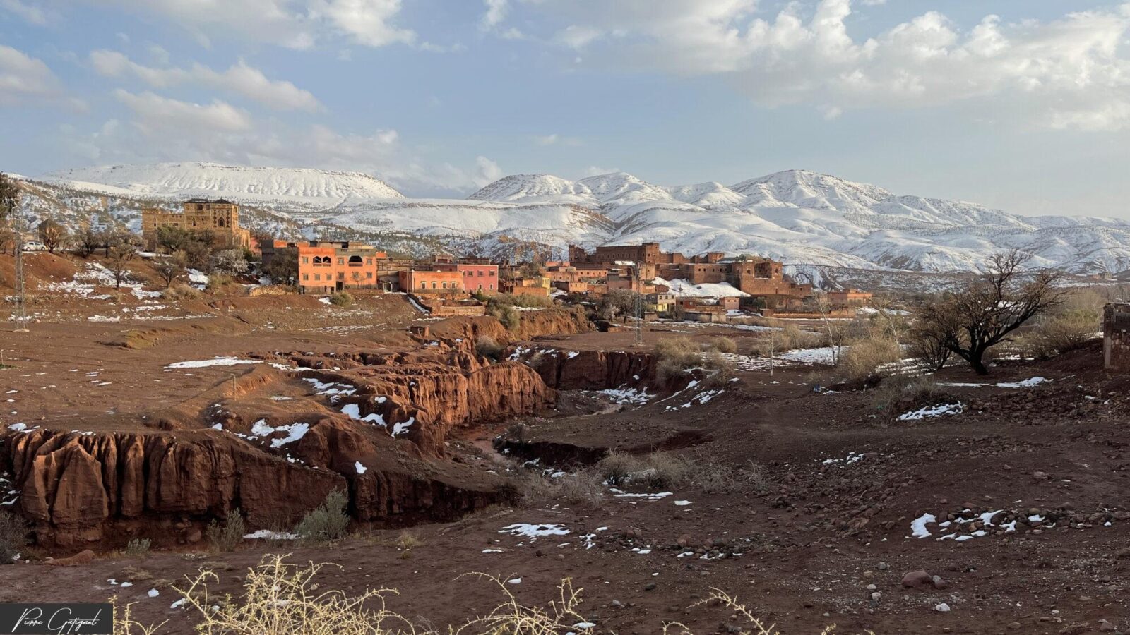 Village aux maisons ocre devant des montagnes enneigées
