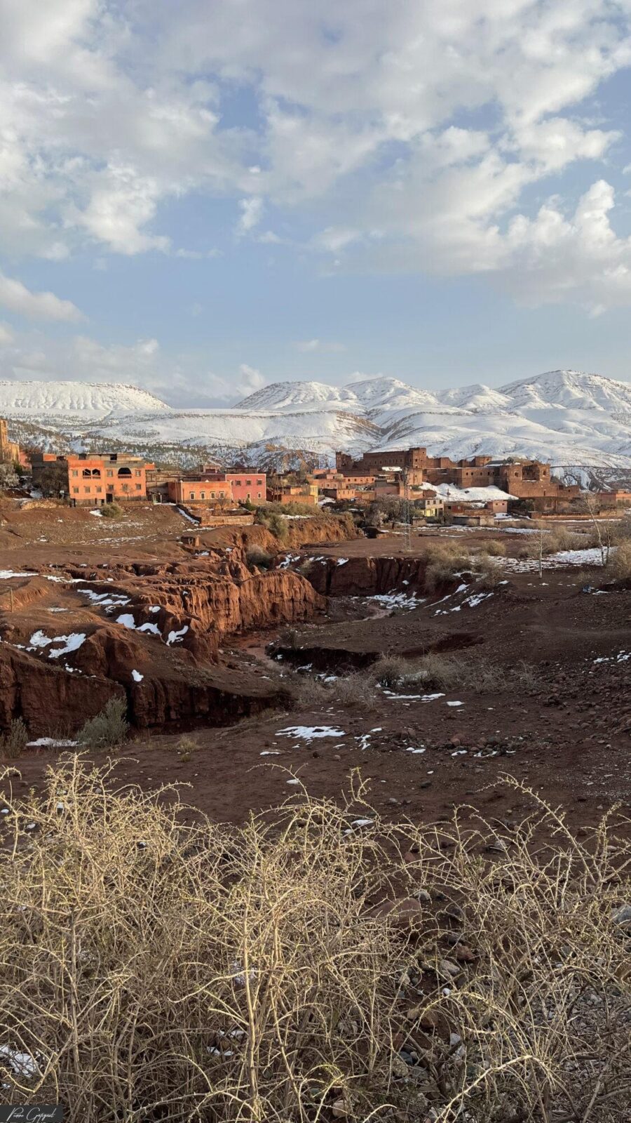 Village au pied de montagnes enneigées sous un ciel nuageux