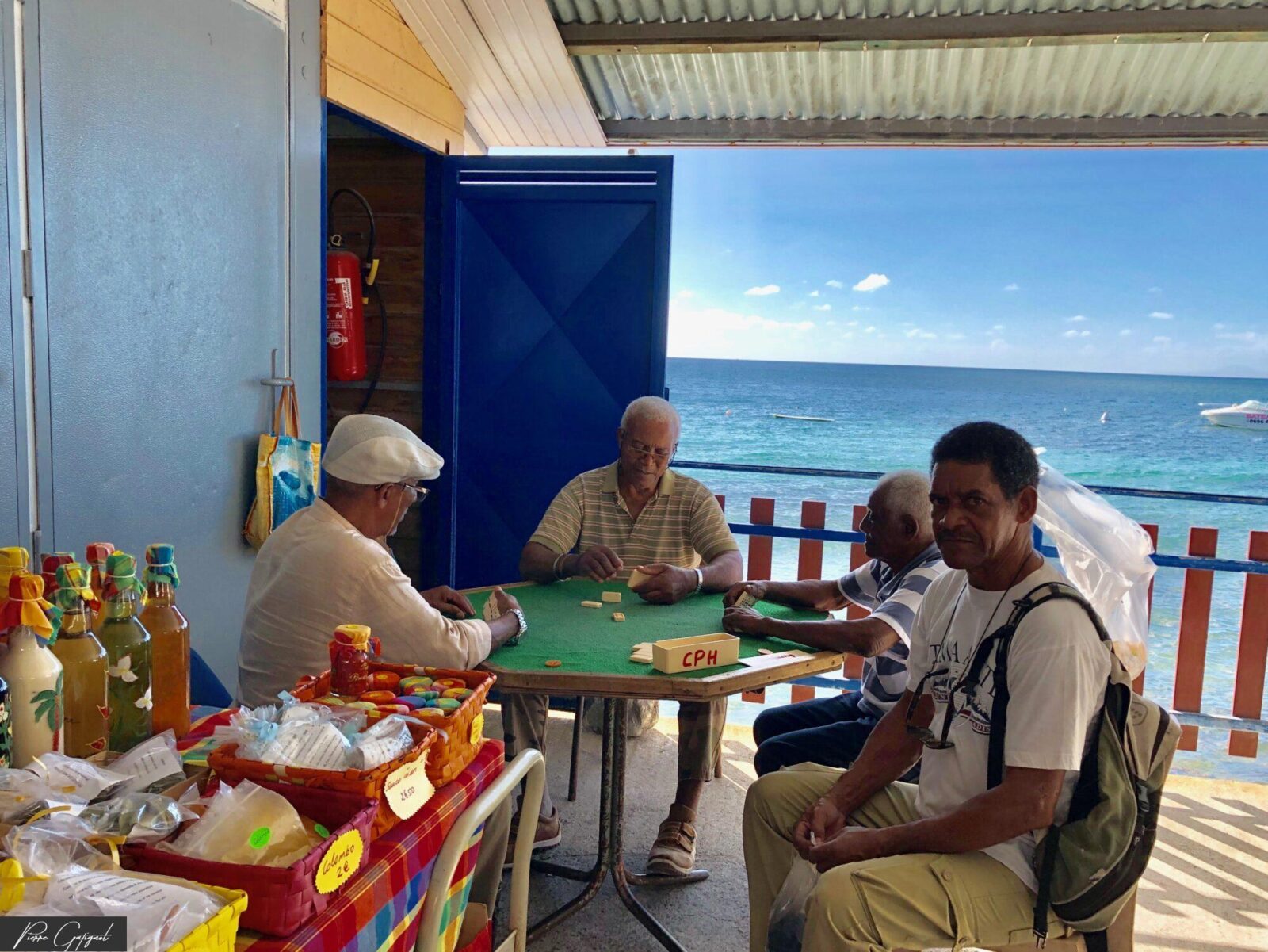 Quatre hommes jouent aux dominos face à la mer