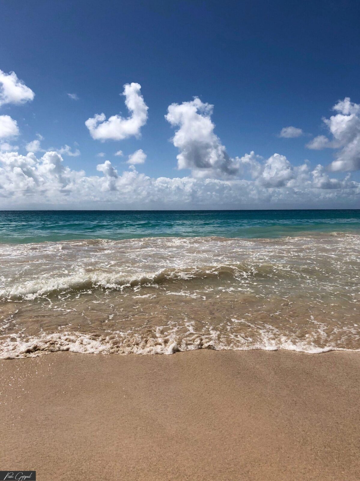 Vagues sur une plage de sable sous un ciel nuageux