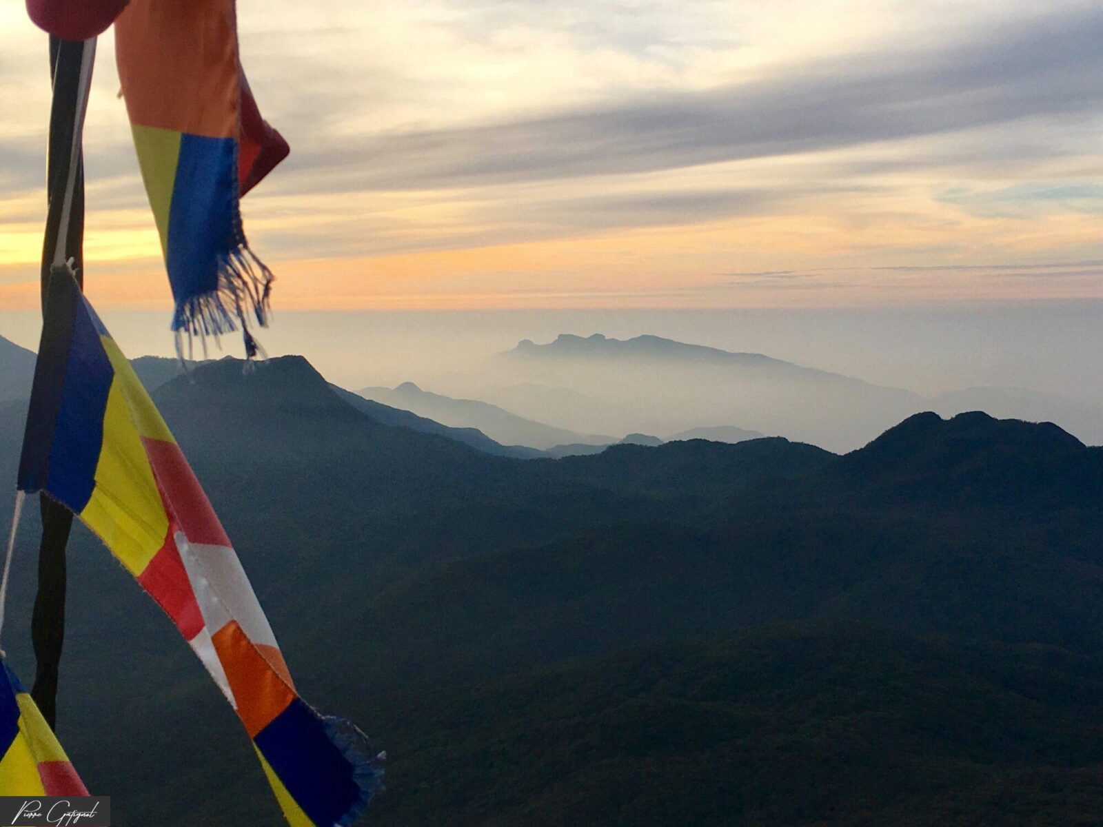 Drapeaux colorés devant des montagnes dans la brume au coucher du soleil