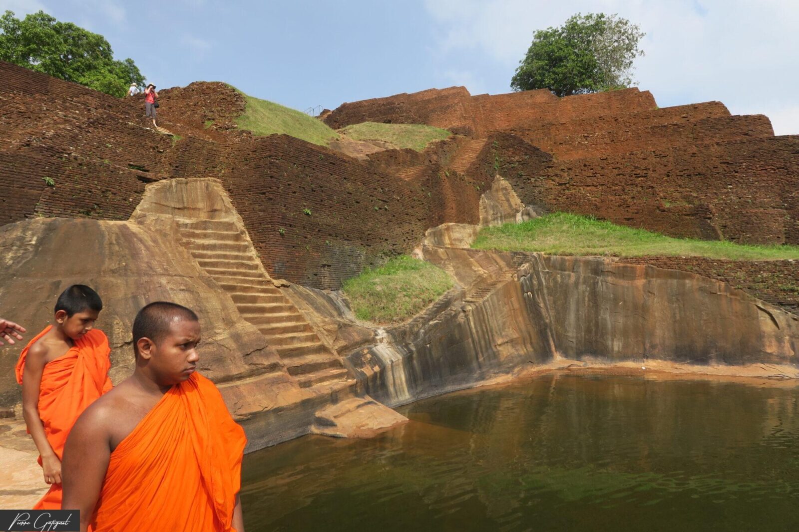 Deux moines bouddhistes en robe orange près d’un bassin et de ruines