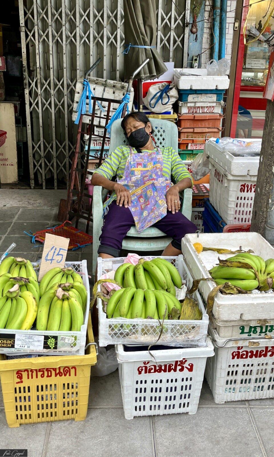 Marchande assise derrière des cagettes de bananes vertes