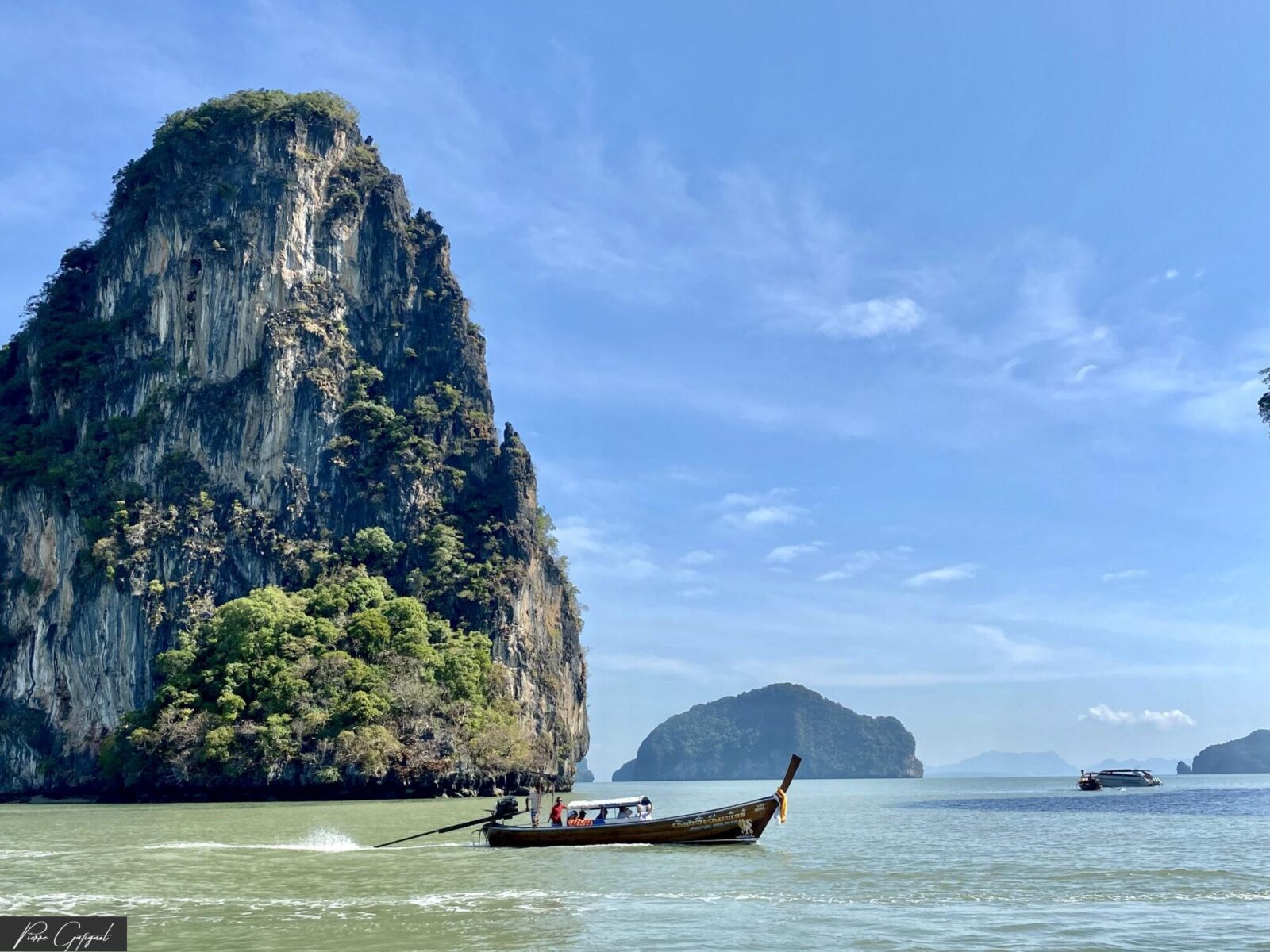 Bateau traditionnel naviguant devant une falaise karstique au bord de la mer