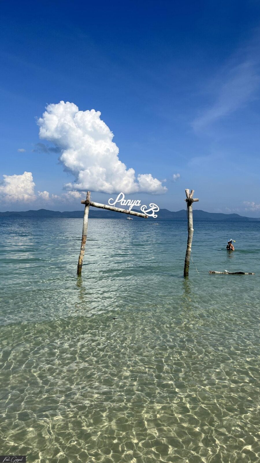 Mer transparente, poteaux en bois et nuages au loin