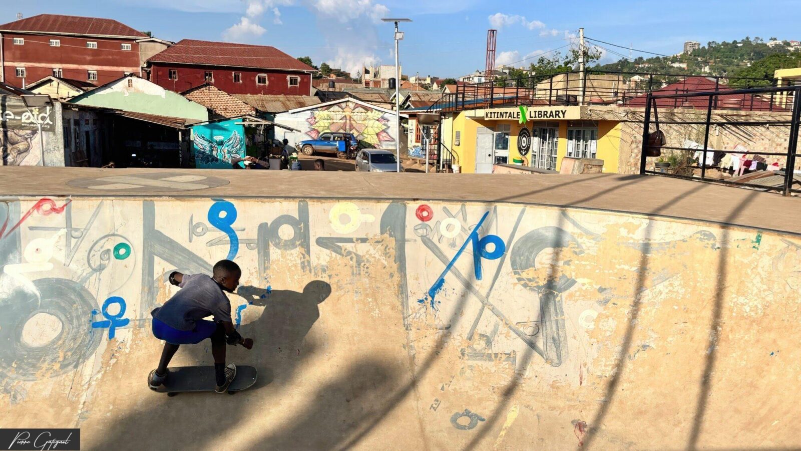 Skateur dans un bowl couvert de graffitis devant une bibliothèque