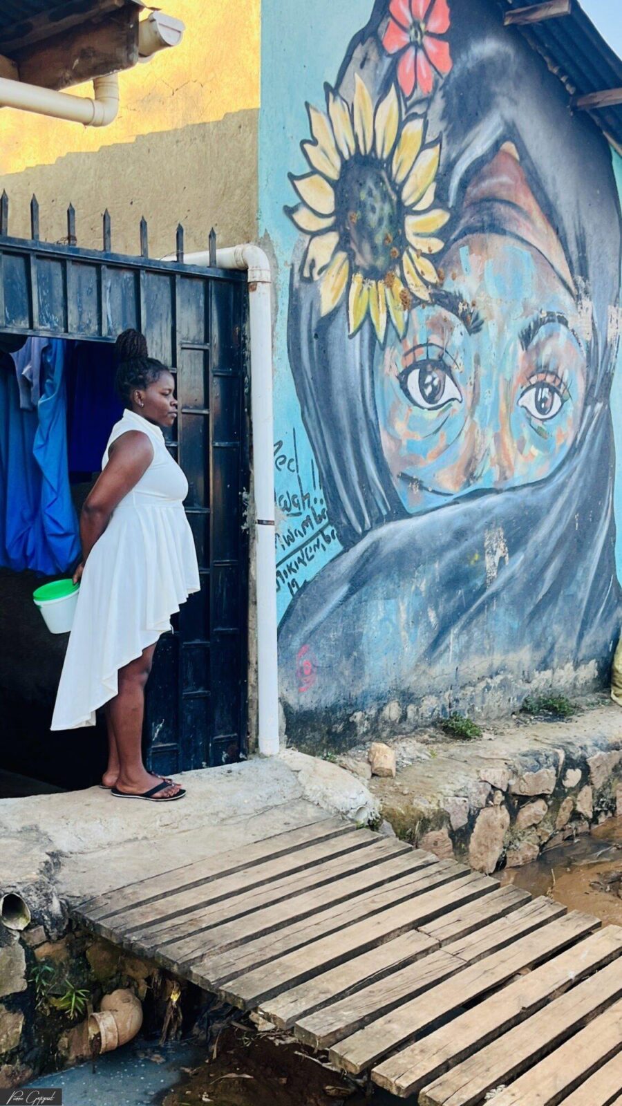 Femme devant un portail et une fresque murale colorée