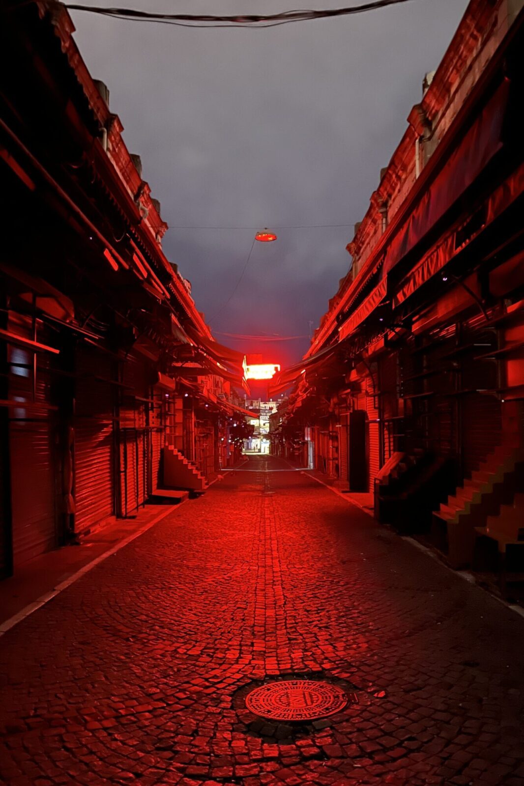 Ruelle pavée vide baignée d’une lumière rouge au crépuscule