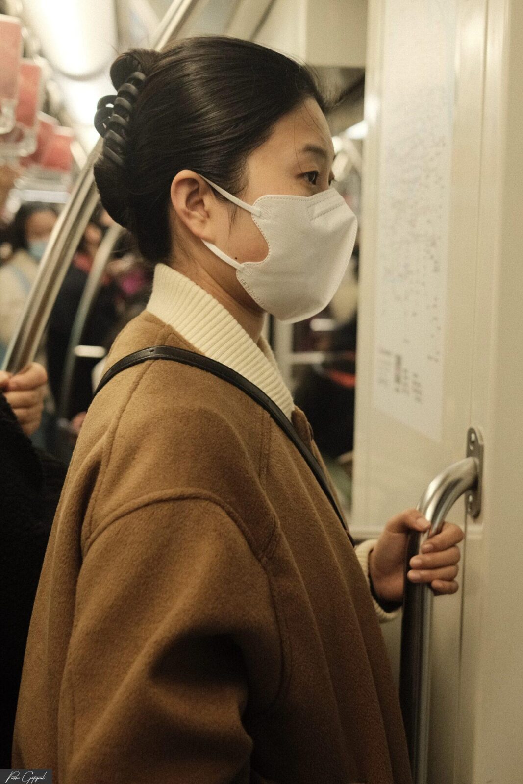 Passagère masquée tenant la barre d’une porte de métro
