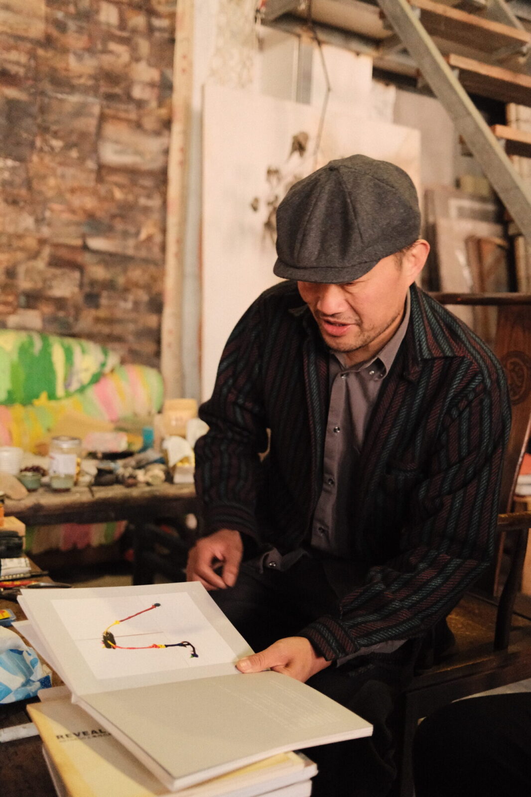 Homme coiffé d’une casquette feuilletant un livre d’art