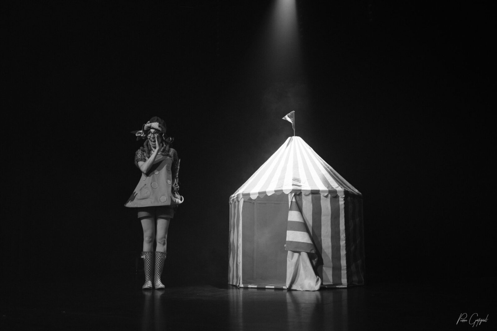 Artiste sur scène devant un petit chapiteau rayé