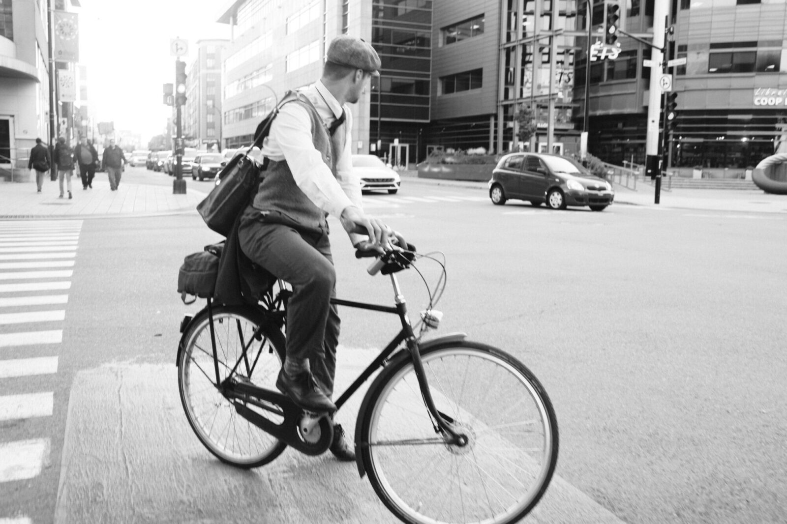 Cycliste traversant une avenue urbaine avec des immeubles modernes