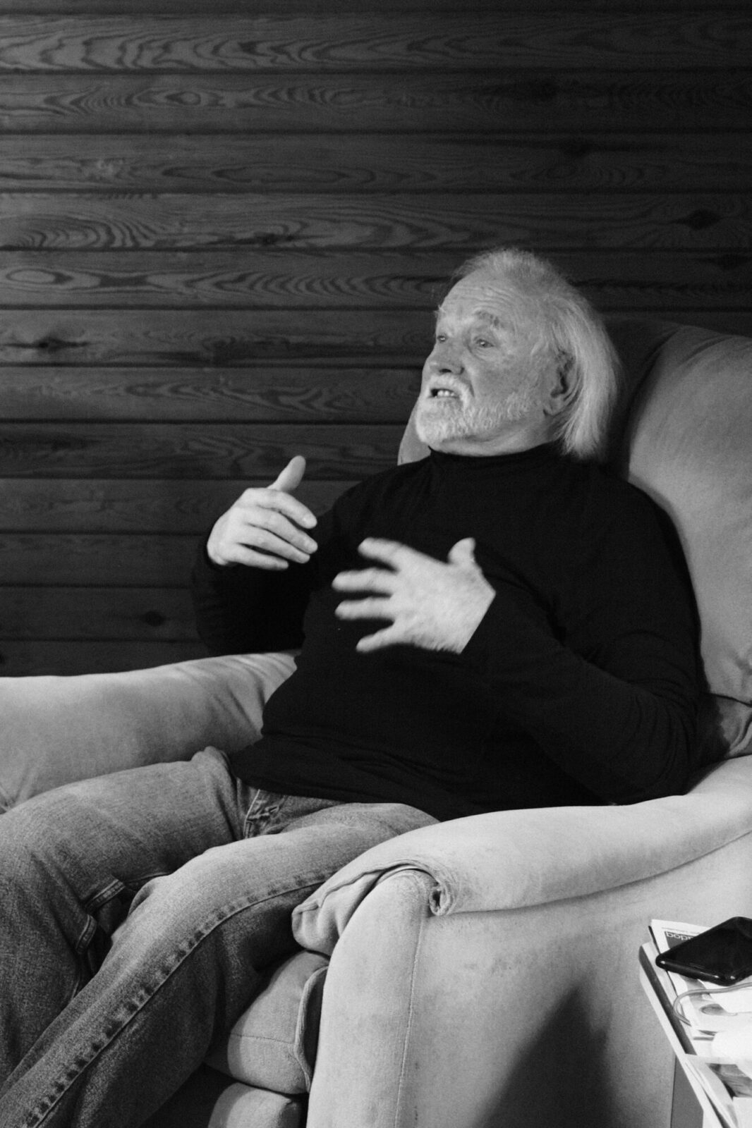 Homme âgé assis dans un fauteuil, gesticulant