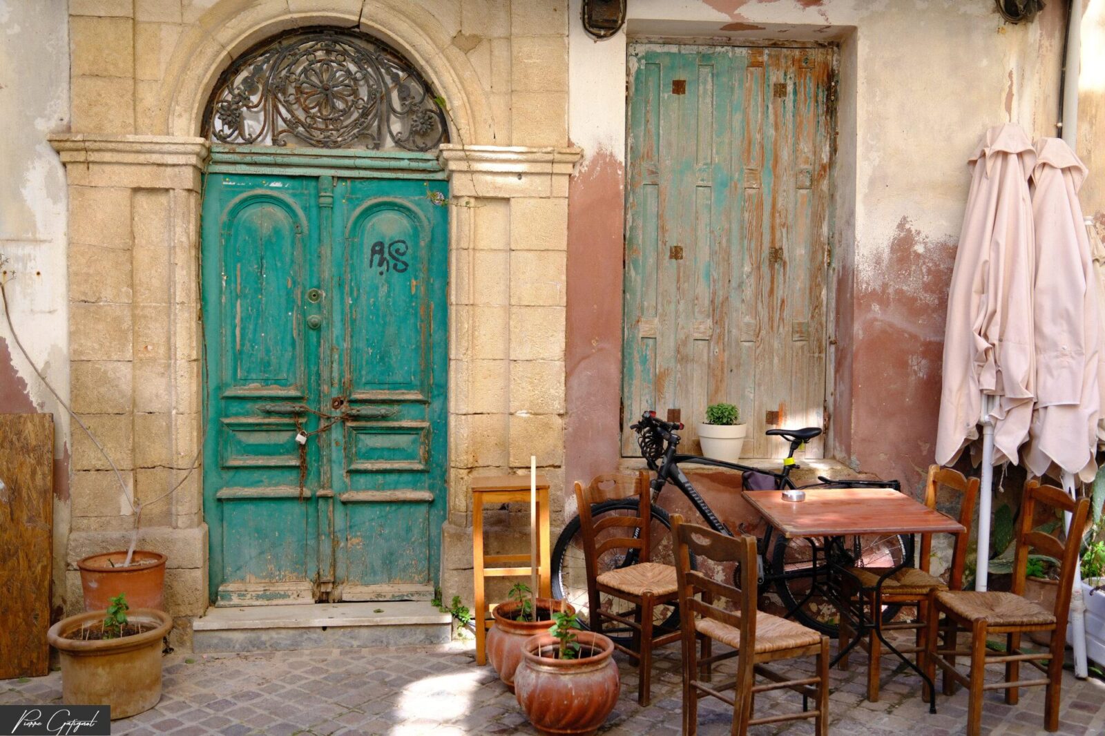 Terrasse avec tables, chaises et portes turquoise patinées