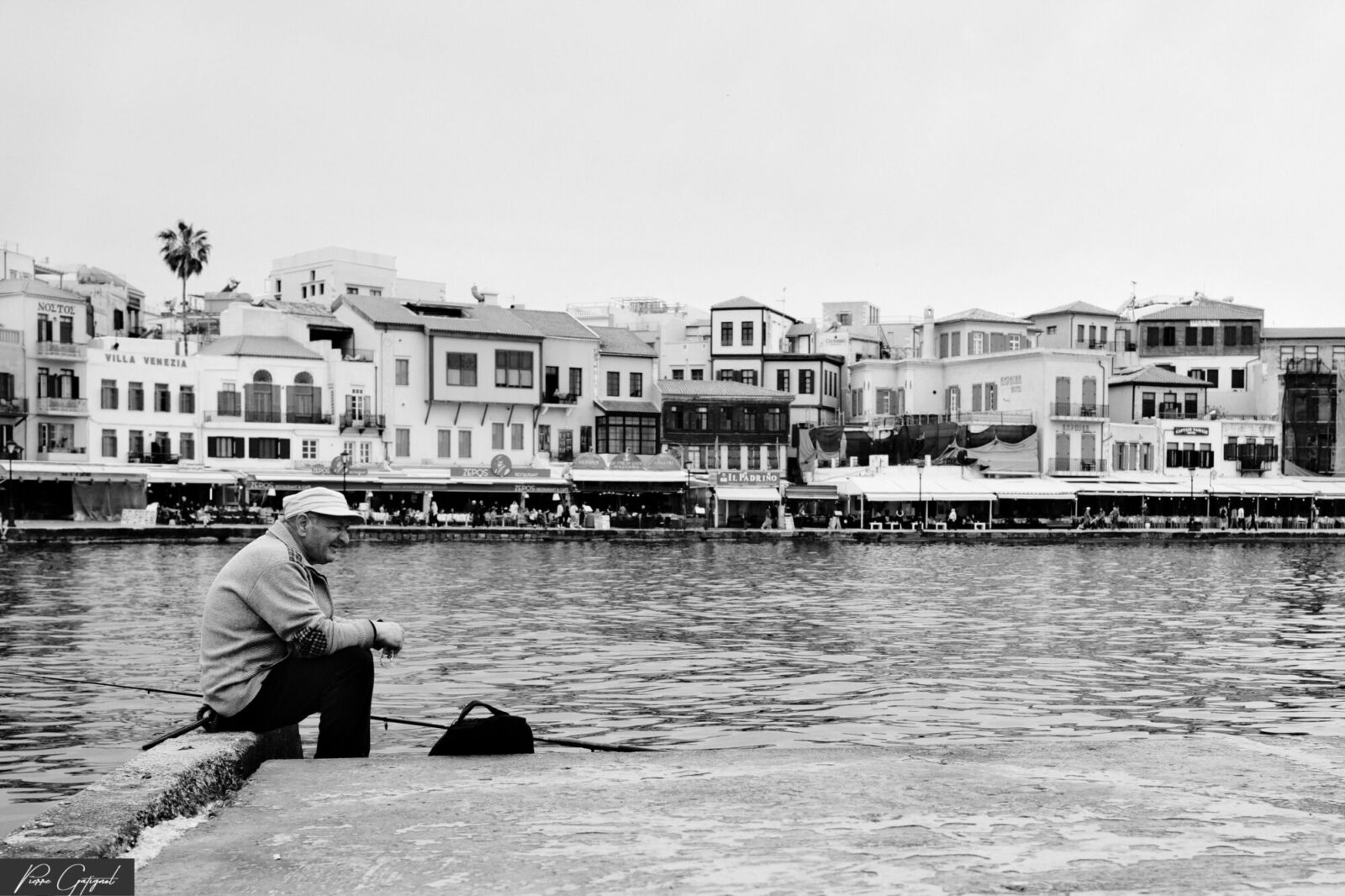 Homme assis sur un quai face à des immeubles au bord de l’eau