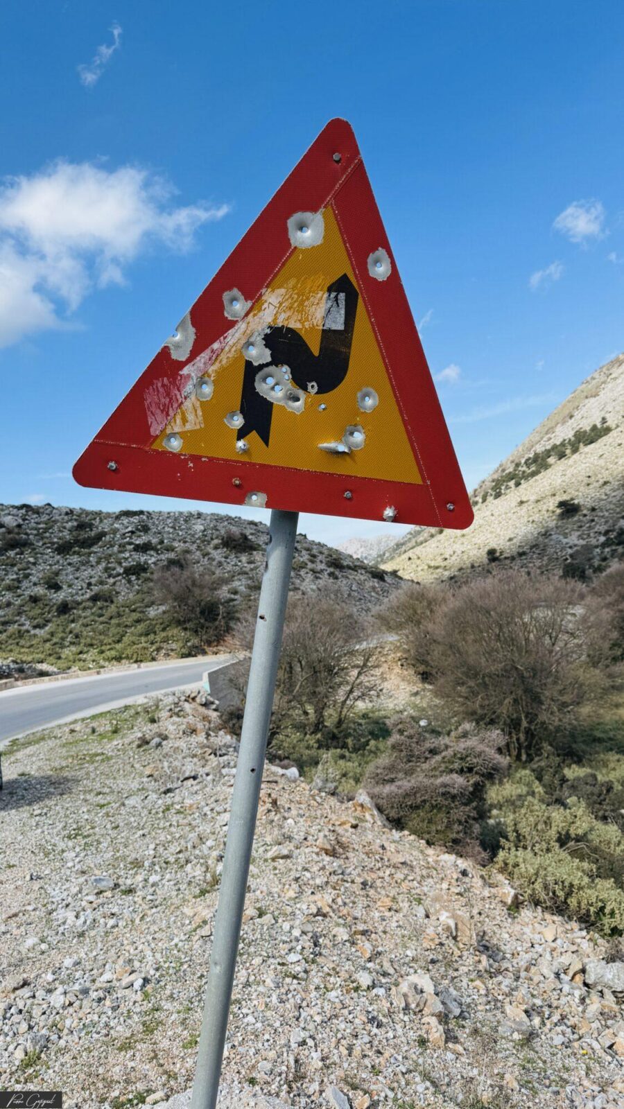 Panneau triangulaire endommagé au bord d’une route de montagne